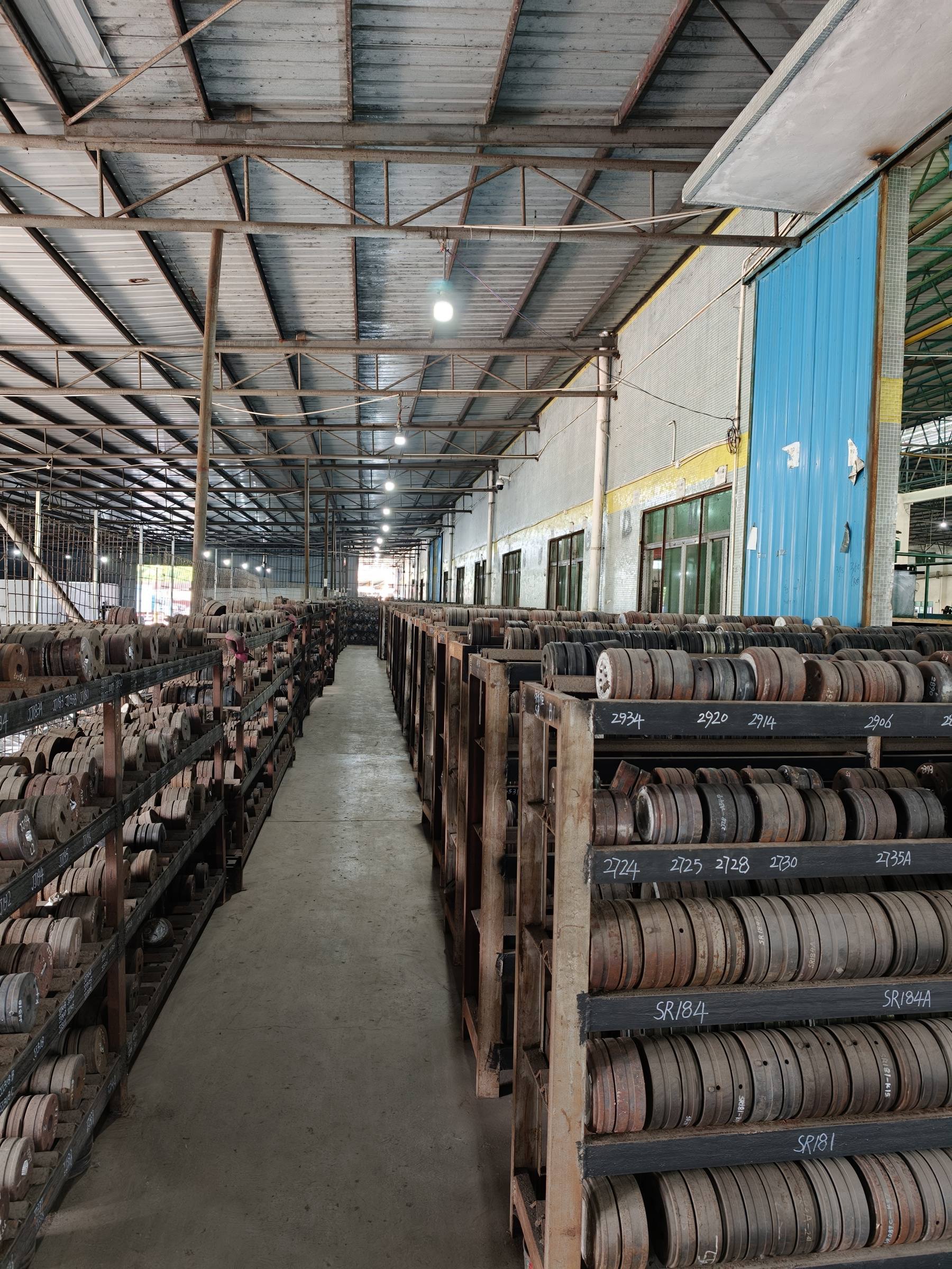 Aisles of numbered extrusion dies stored on racks in the mold library